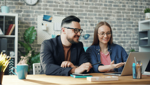 Two people discussing a project while using a laptop