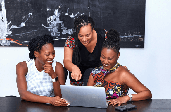 Three colleagues laughing and pointing at a laptop screen