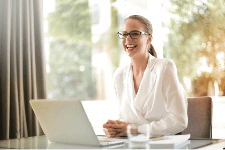 A smiling businesswoman smiling at a desk, with her hands together