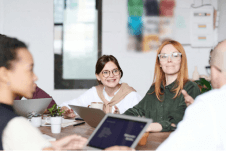 A happy team, smiling around a meeting table