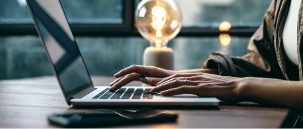 A laptop being used next to a lamp on a desk