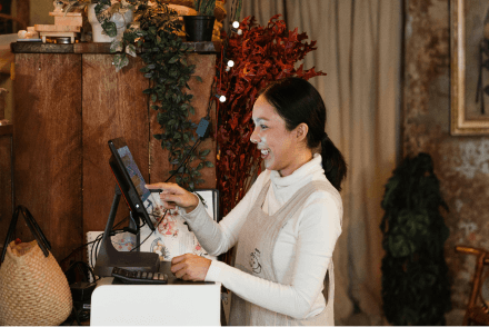 A retail staff member using the till to serve a customer