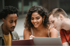 A team of three having a catchup outside, using their laptops