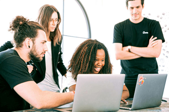 A team of four people looking at a laptop